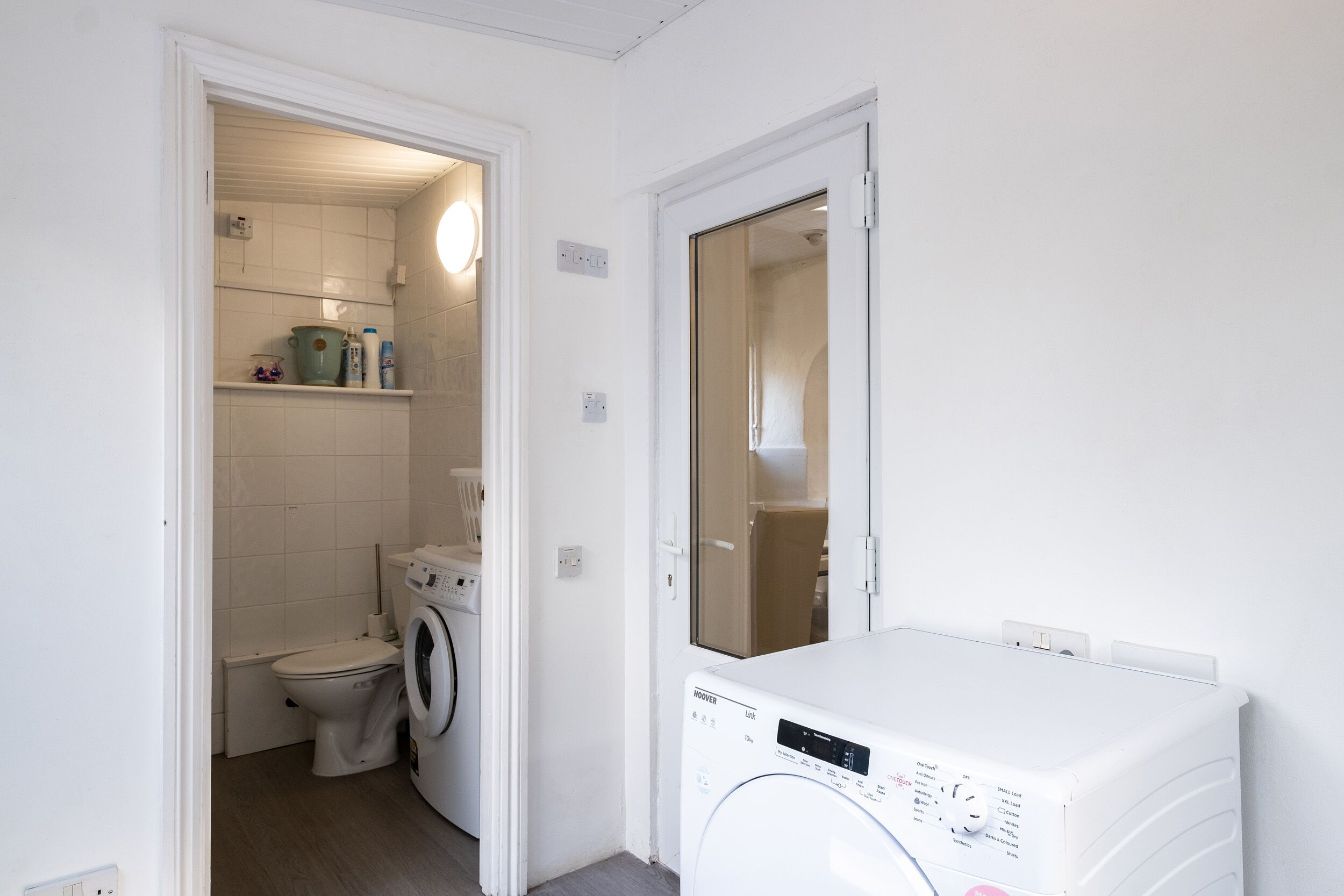 Uma lavanderia compacta com máquina de lavar, secadora e vaso sanitário.
