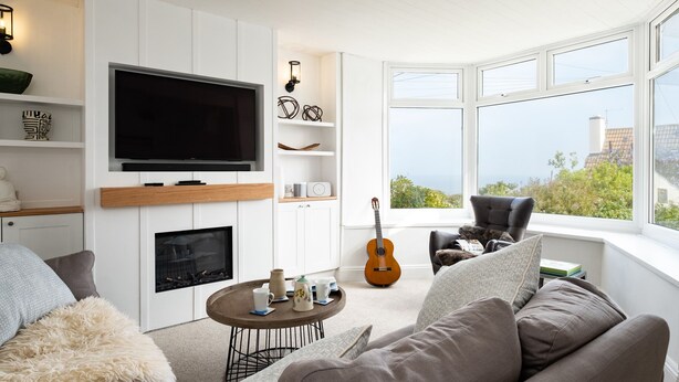 A modern living room with a flat-screen TV, fireplace, and a view of the outdoors. - Seapinks (Port Isaac)