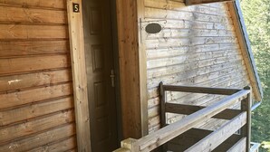 A wooden cabin with a wooden staircase leading to a balcony. - Duplex N°5 Résidence Puy du Rocher (Le Lioran)