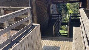 A wooden deck with a metal grate, a wooden staircase, and a view of a mountain range. - Duplex N°5 Résidence Puy du Rocher (Le Lioran)