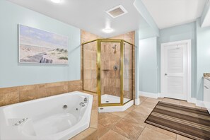 A bathroom with a glass-enclosed shower, a bathtub, and a door with a white handle.