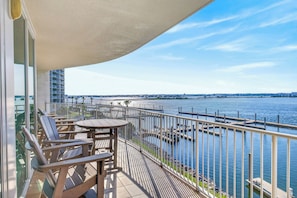 A balcony with outdoor furniture, a view of the water, and a distant cityscape. - PROFESSIONALY DECORATED, 3 BED 3 BATH UNIT!!! ASK ABOUT DISCOUNTS! (Orange Beach)