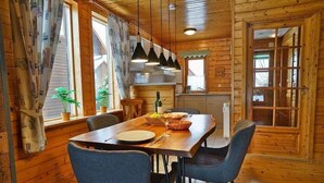 Un intérieur en bois comprenant une table à manger, des chaises et un coin cuisine.