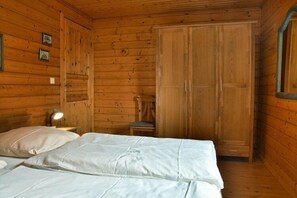 Una habitación de madera con una cama, una silla y un armario.