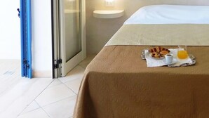 A hotel room with a bed, a table with breakfast items, and a towel. - Monolocale Torre San Giovanni Verso Sud (Ugento)