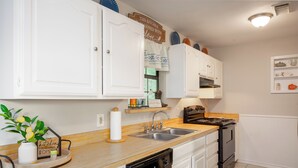 A kitchen with white cabinets, a wooden countertop, a dishwasher, a stove, and a sign on the wall.