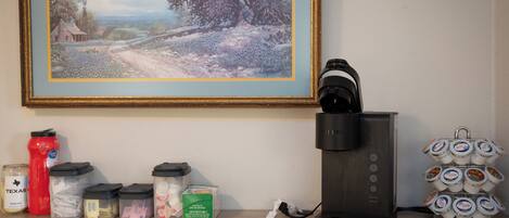 A coffee maker, a water bottle, and containers of coffee creamer on a shelf.