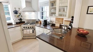 Una cocina moderna con armarios blancos, una estufa de acero inoxidable y un amplio ventanal que proporciona luz natural.