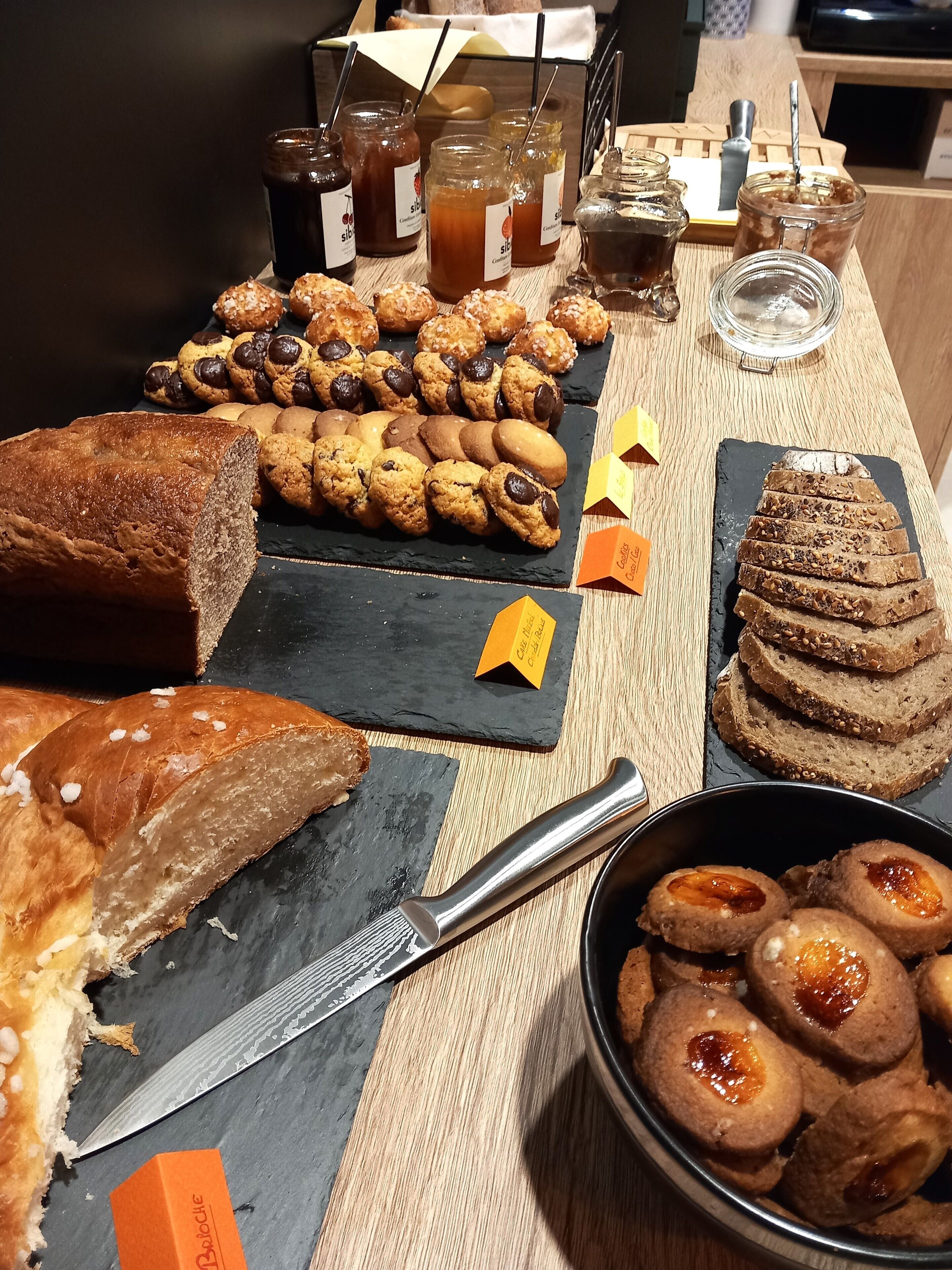 Une variété de produits de boulangerie, notamment du pain, des biscuits et des pâtisseries, disposés sur une table en bois.