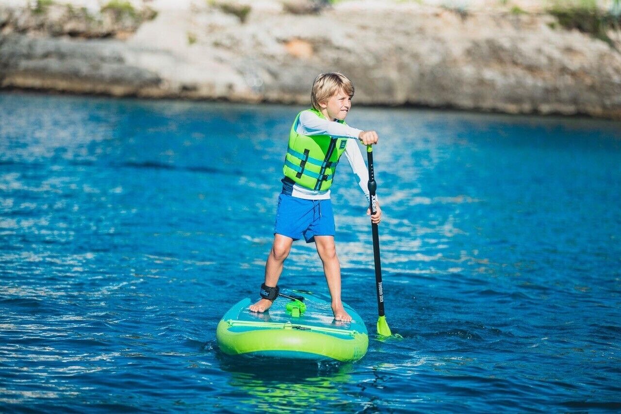 Een kind op een groene paddleboard in het water.