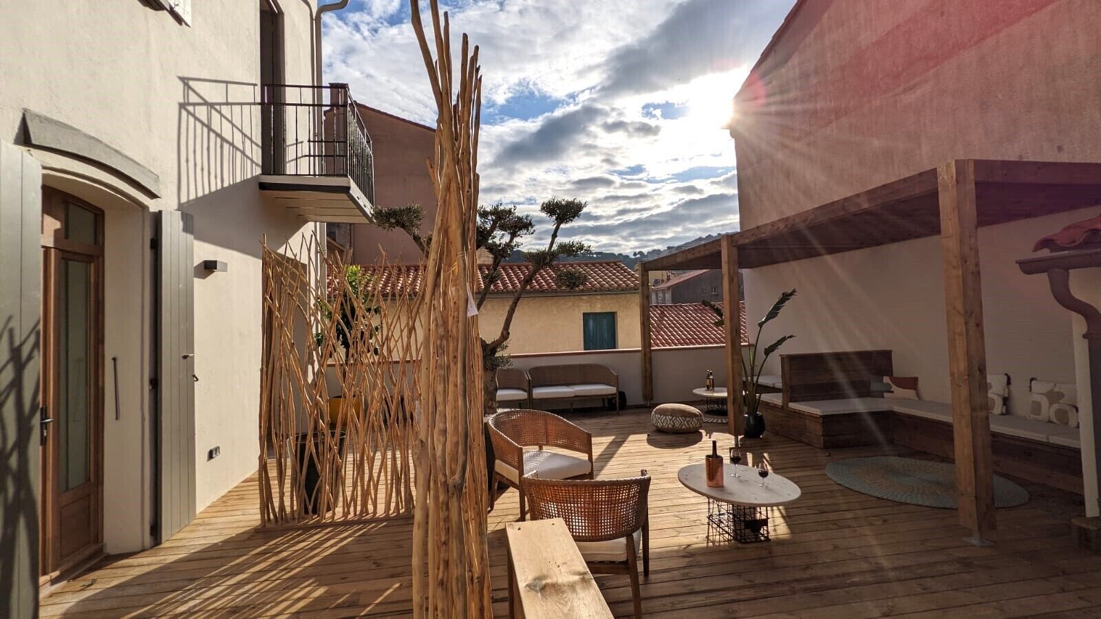 Une terrasse en bois avec des sièges extérieurs, un espace couvert et un bâtiment doté d’un balcon.