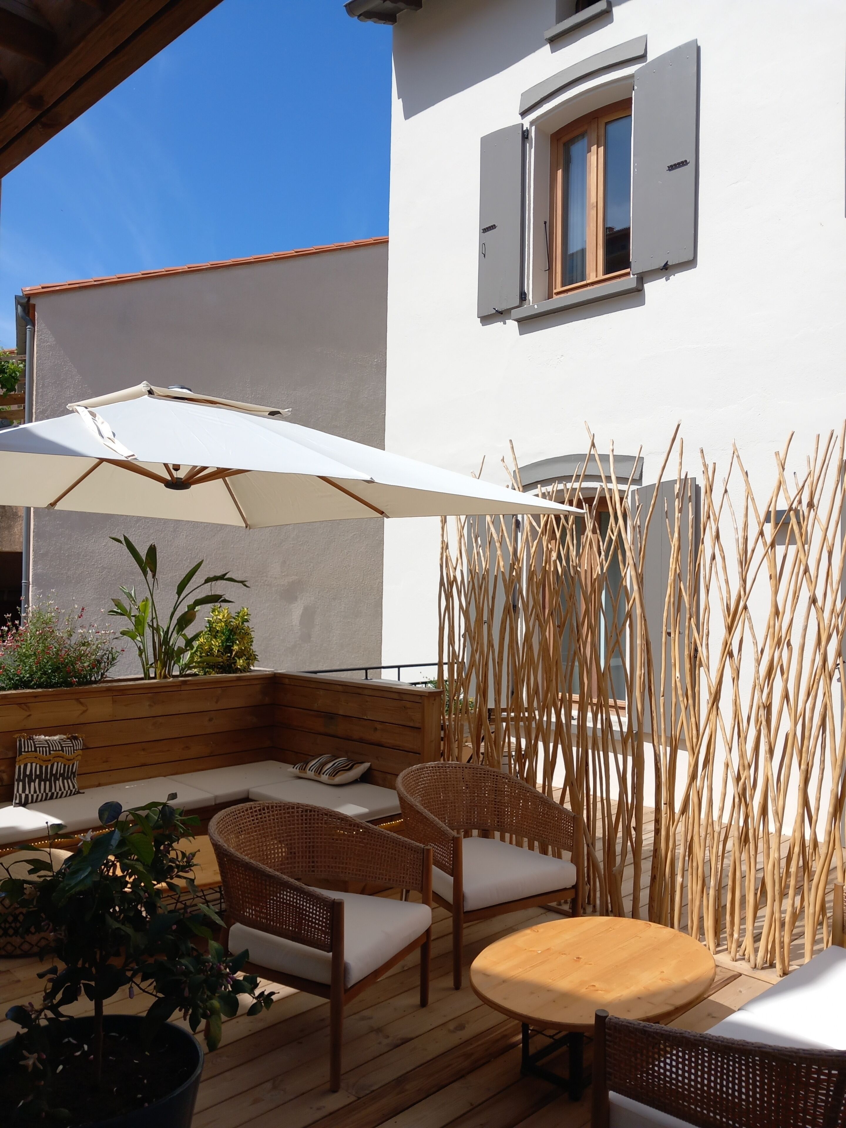 An outdoor seating area with wicker furniture and a large umbrella.