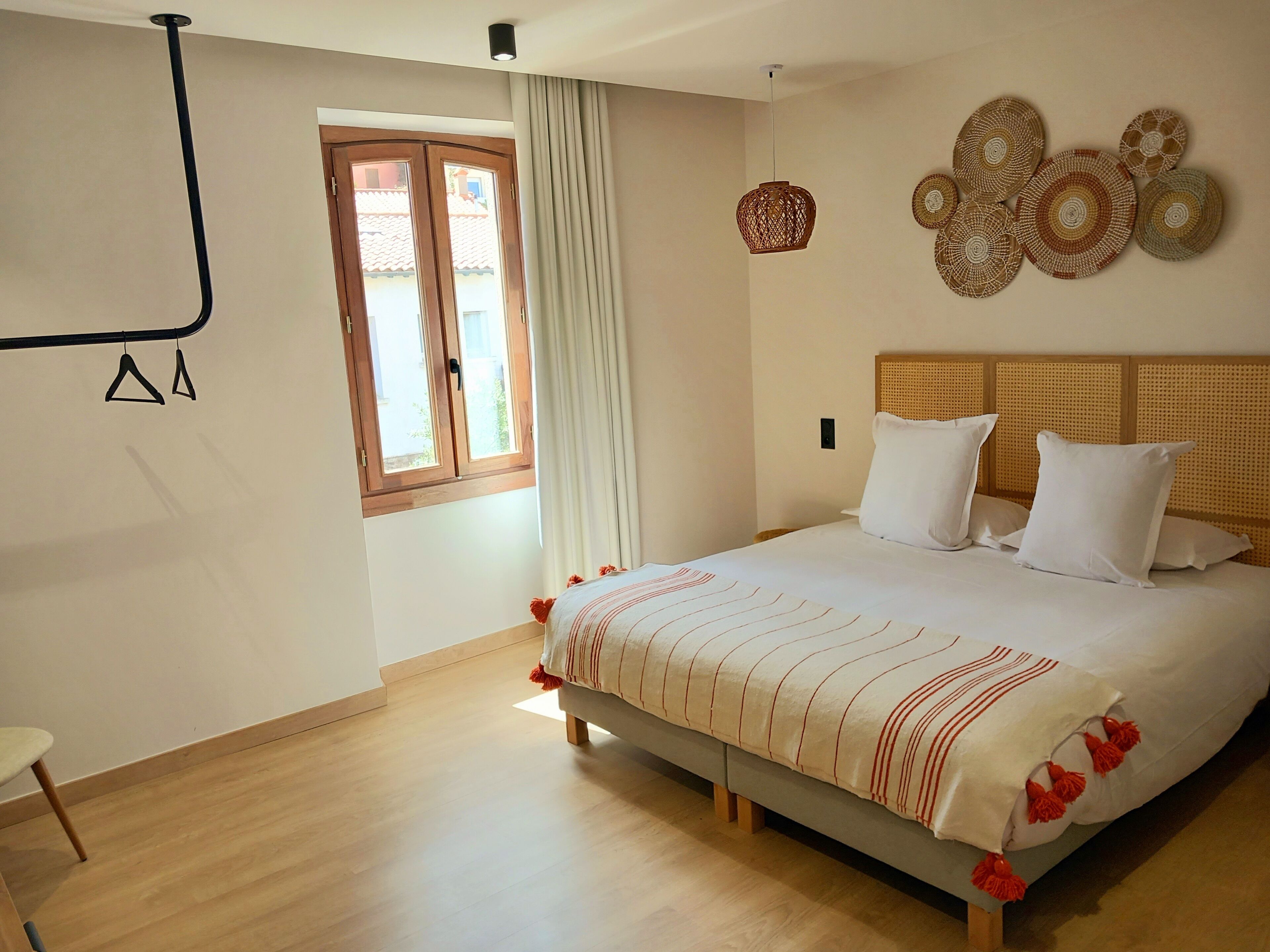 Une chambre à coucher avec un lit, une fenêtre avec des rideaux, un luminaire fixé au mur et un élément décoratif mural.