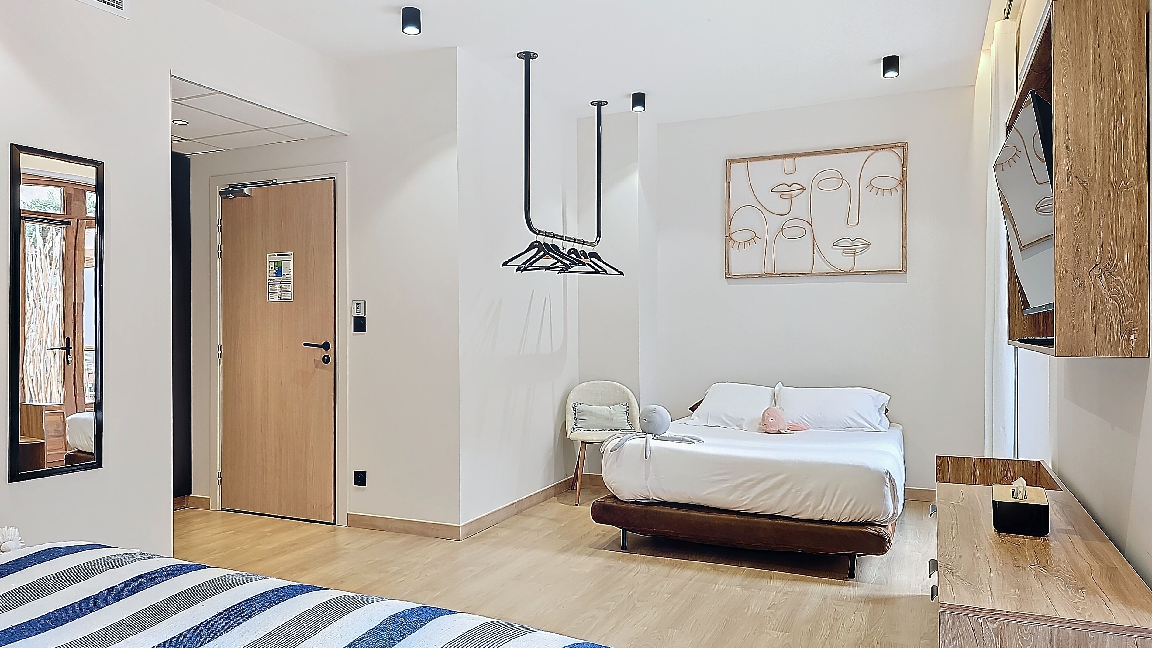 Ein Schlafzimmer mit einem Bett, einer Holztür, einer Hängeleuchte und einem Wandbild.