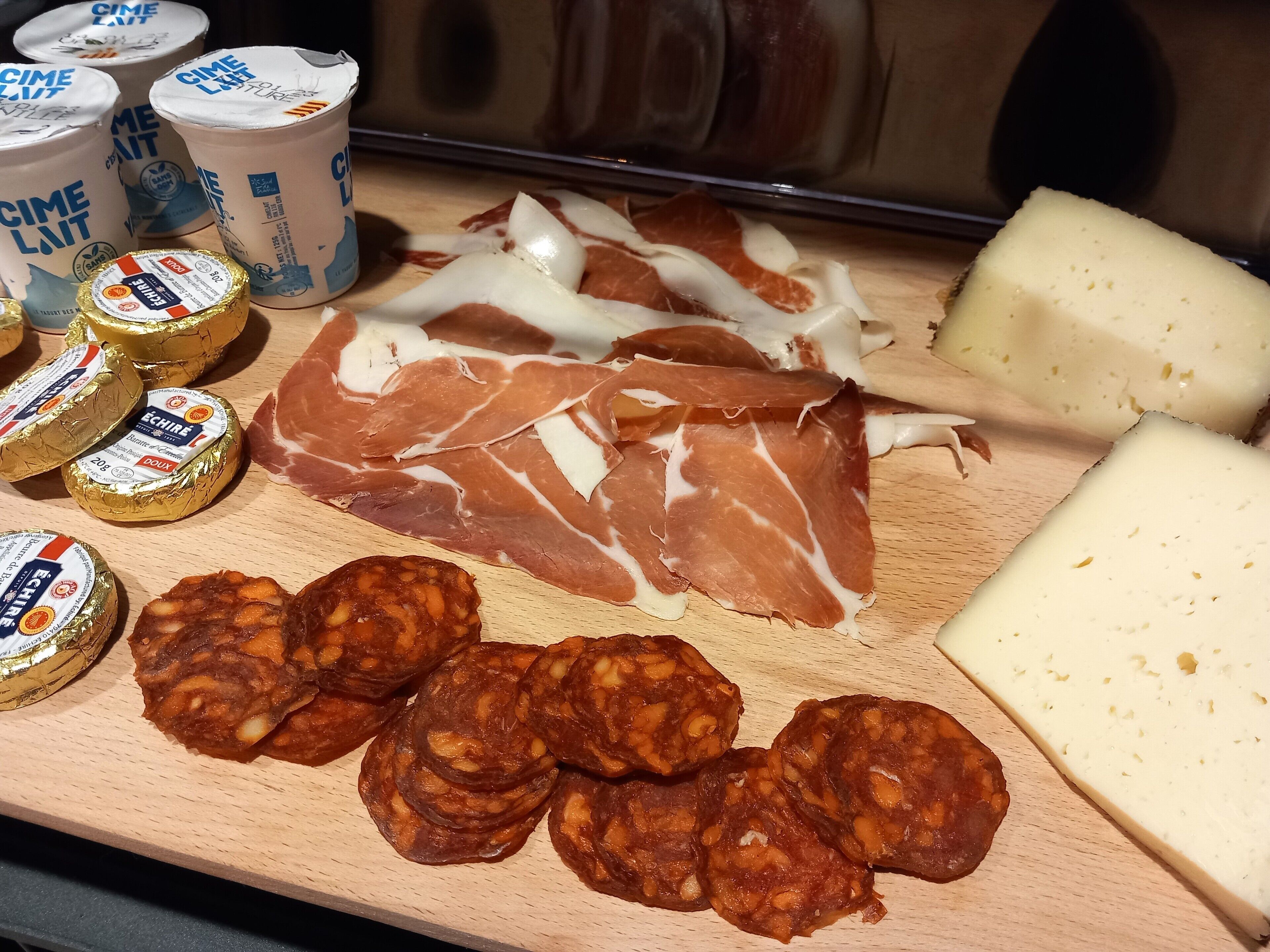 Ett urval av lufttorkat kött, inklusive prosciutto och salami, samt ost, serverat på en träbricka.