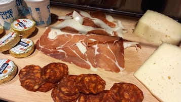 Ett urval av lufttorkat kött, inklusive prosciutto och salami, samt ost, serverat på en träbricka.