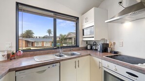 Una cocina moderna con un ventanal grande, electrodomésticos de acero inoxidable y vistas a casas vecinas.