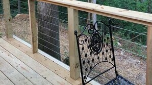 Eine Holzterrasse mit Metallgeländer, umgeben von Bäumen.