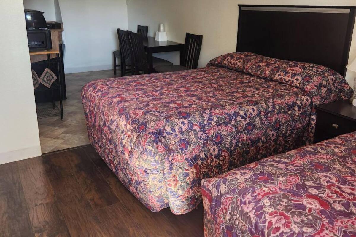 A bedroom with two beds, a desk, and a chair.