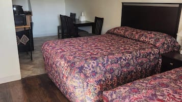 A bedroom with two beds, a desk, and a chair.