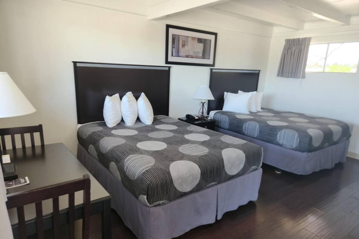A hotel room with two single beds, a desk, and a chair.