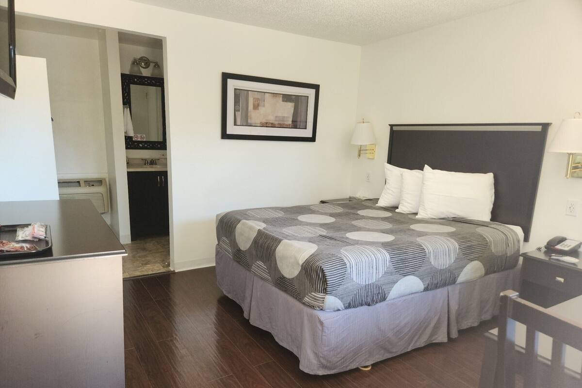 A hotel room with a bed, bedside lamps, a framed picture on the wall, and a desk with a telephone.