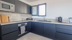 Una cucina moderna con mobili scuri, forno a microonde integrato, lavello doppio e macchina per il caffè.