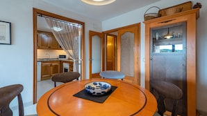 Un coin repas avec une table ronde en bois, un saladier bleu et blanc, et des chaises à l’assise rembourrée de couleur marron.