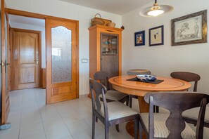 A dining area with a round wooden table, six chairs, a cabinet with glass doors, and framed artwork on the wall.