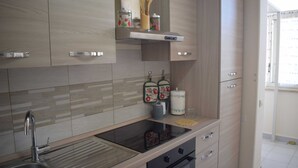 A modern kitchen with a stainless steel sink, wooden cabinets, a built-in oven, and a countertop with kitchen utensils.