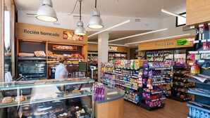 A bakery section with a display case of baked goods and a counter with a person behind it.