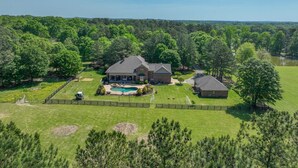 A large house with a swimming pool, surrounded by a fenced yard and wooded area. - Hidden Haven on 9 acre, pond, barn and more, sleeps 20 (Stanfield)