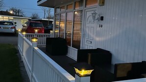 Een motel met een witte gevel, een overdekte buitenruimte met zwarte meubels en het nummer '30' op de deur.