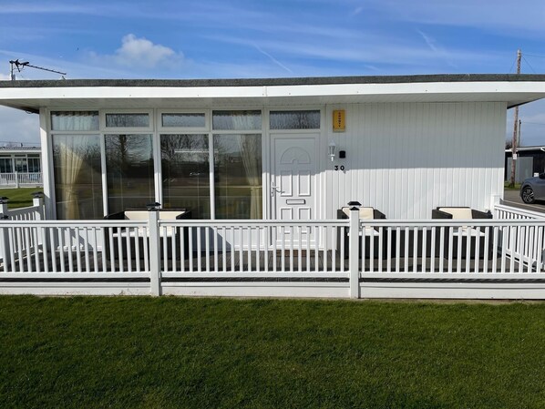 A white building with a covered patio area, a door, and a number '30' sign.
