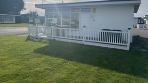 Een witte stacaravan met een omheind terras, nummer 30, in een woonwijk.