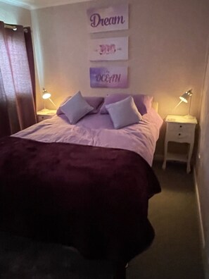 A bedroom with a bed, two bedside tables with lamps, and wall art.