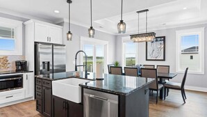 Una cocina moderna con electrodomésticos de acero inoxidable, una isla grande e iluminación colgante.