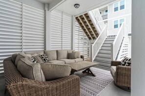 Ein Wohnzimmer mit einem Ecksofa, einem Couchtisch, Korbstühlen und einem gemusterten Teppich.