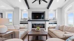 Una sala de estar moderna con chimenea, sofás, una mesa de centro y un televisor.