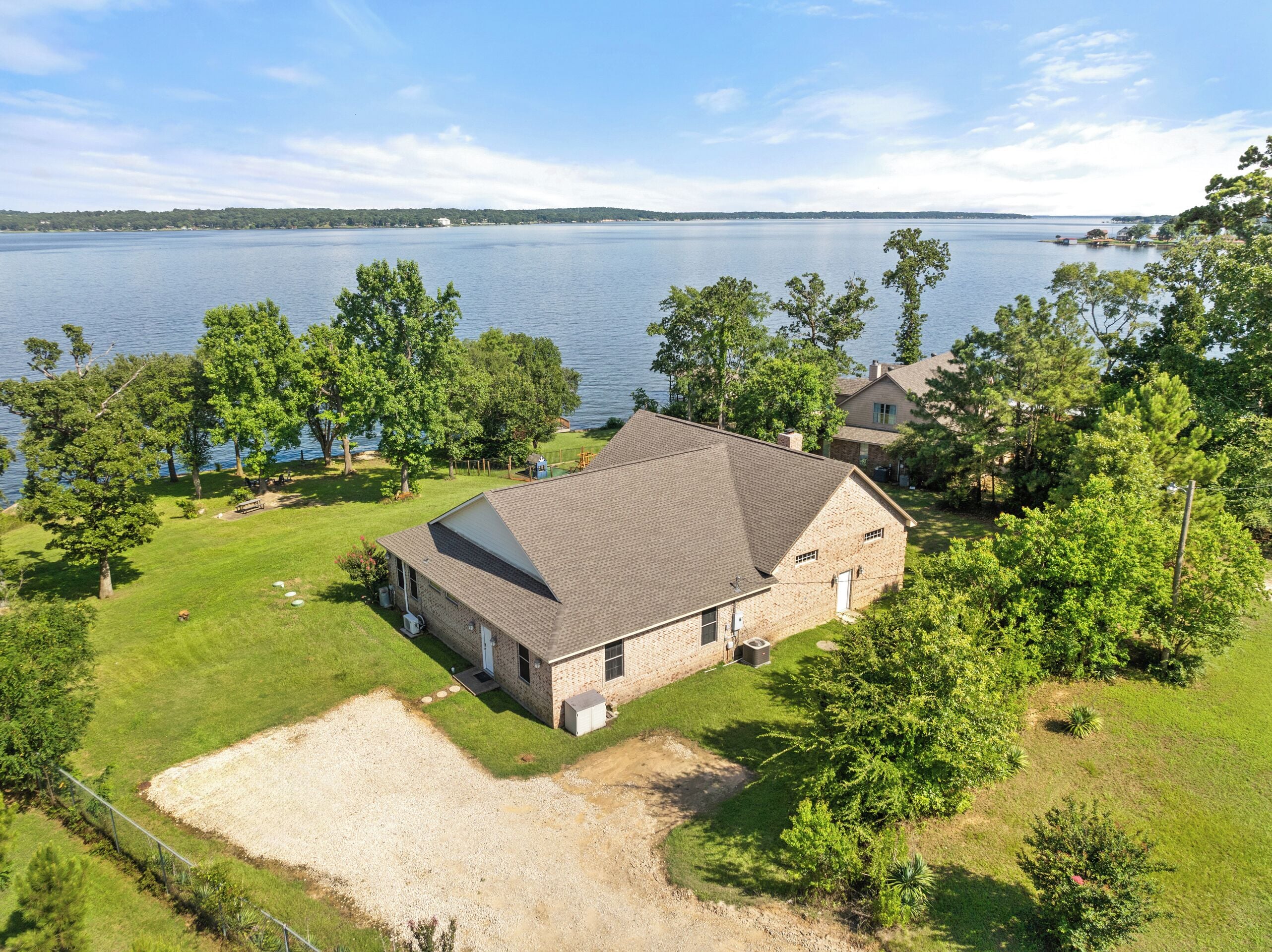 A house with a sloped roof, a fenced yard, and a view of a large body of water.
