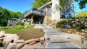 A modern house with a stone staircase leading to a wooden deck. - SO 68 Perch Cove (South Kingstown)