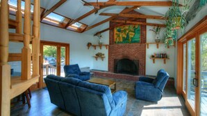 A cozy living room with a fireplace, blue sofas, and wooden beams. - SO 68 Perch Cove (South Kingstown)