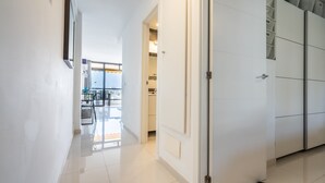 A modern hotel corridor with a clean, white interior, a glass door leading to a dining area, and a wardrobe with storage compartments. - APARTMENT IN VIÑA DEL MAR - PLAYA DE LAS AMERICAS (Costa Adeje)