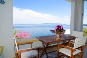 Une table et des chaises en bois sur un balcon offrant une vue sur la mer et les montagnes.