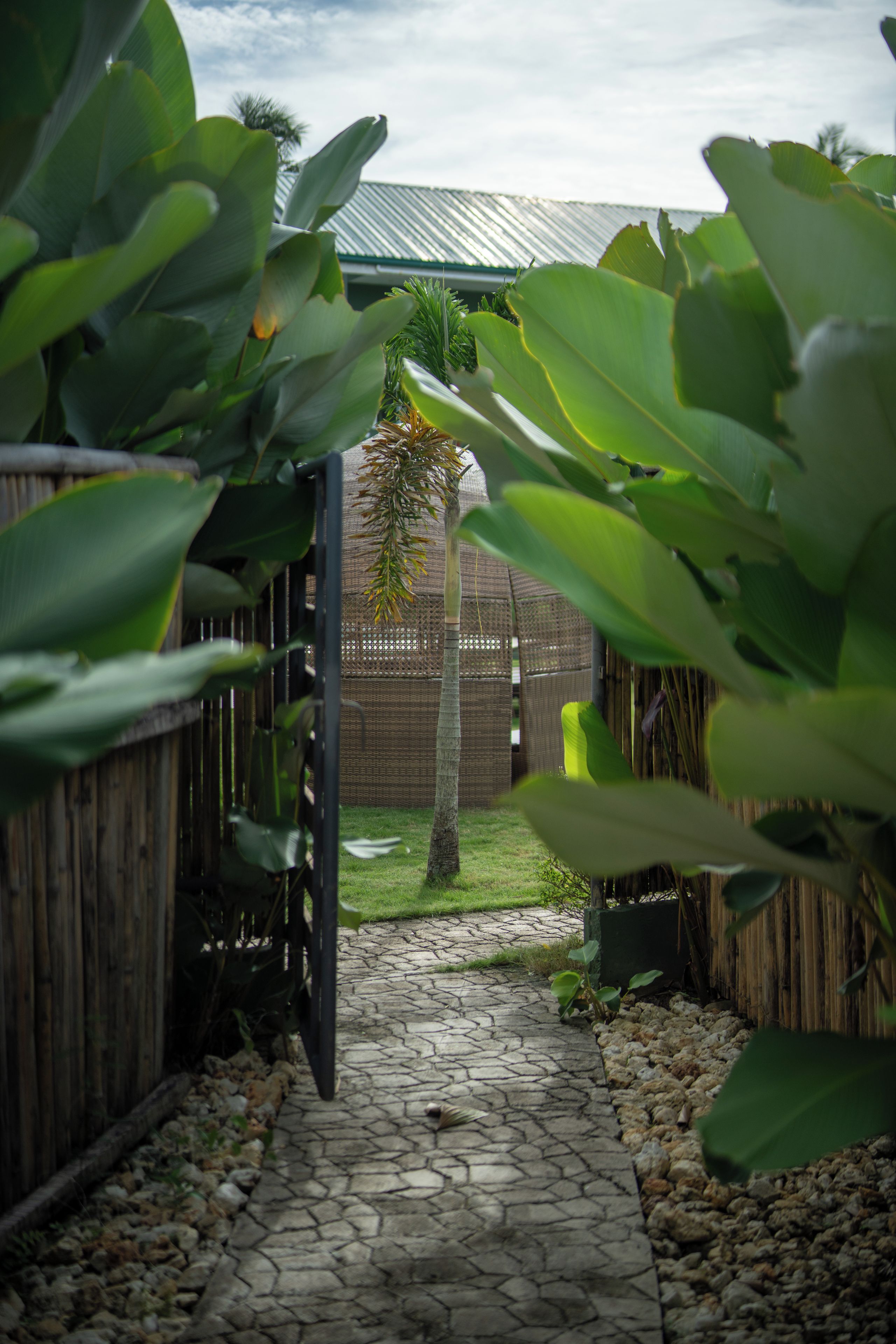Een pad van stenen leidt naar een houten poort, omringd door weelderig groen.