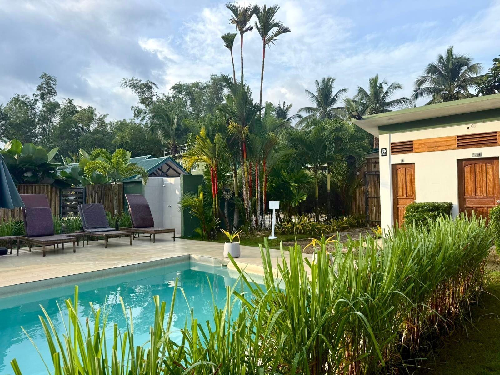 A pool area with lounge chairs and a small building with a green roof.