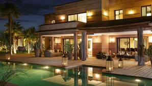 Una casa moderna con piscina, mobiliario exterior y una gran estatua de elefante.