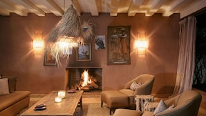 Una sala de estar acogedora con chimenea, asientos cómodos e iluminación en la pared.