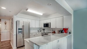 Una cocina moderna con armarios blancos, electrodomésticos de acero inoxidable y encimera de mármol.
