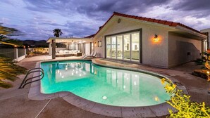 A modern house with a swimming pool, a patio with outdoor furniture, and a large glass door leading to a covered area. - Stunning Lake View, Heated Pool, Single Story! (Boulder City)